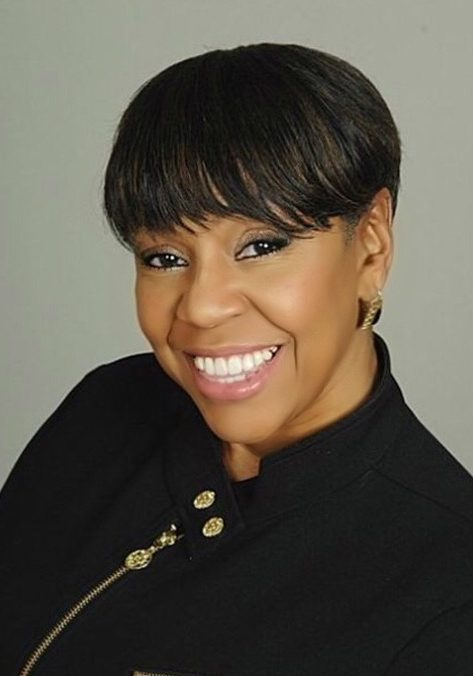 Headshot of woman smiling in black jacket with gold zipper